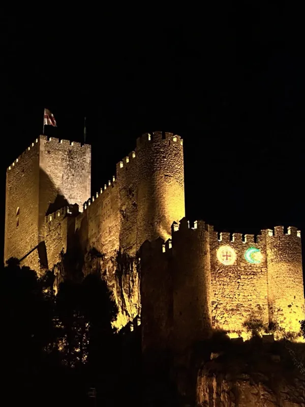 Foto original de un castillo iluminado de noche, en la página izquierda