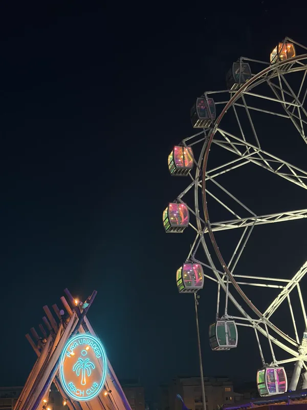 Foto nocturna de una noria de feria con cabinas iluminadas